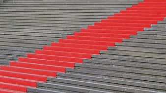 Red Carpeted Staircase Steps Against Gray Concrete Architecture