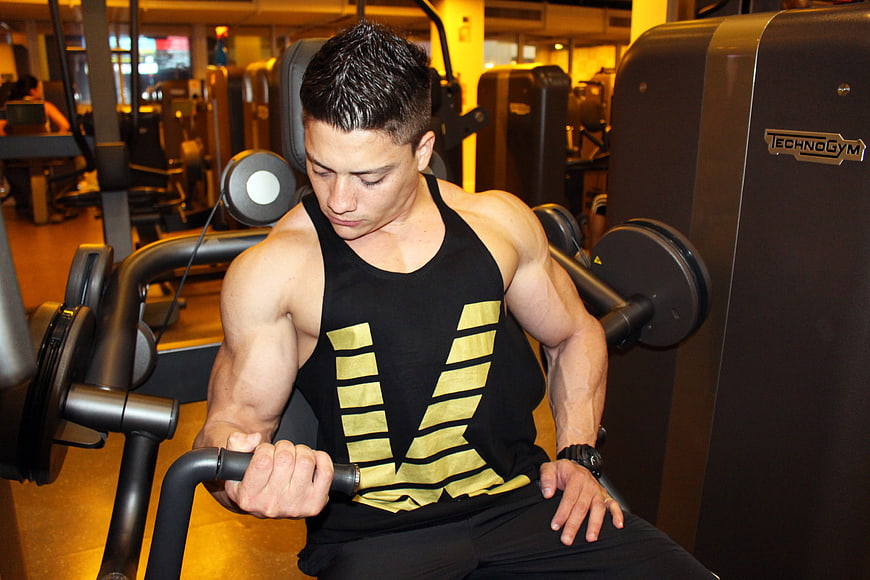 Muscular Asian man performing seated cable row exercise in a modern gym