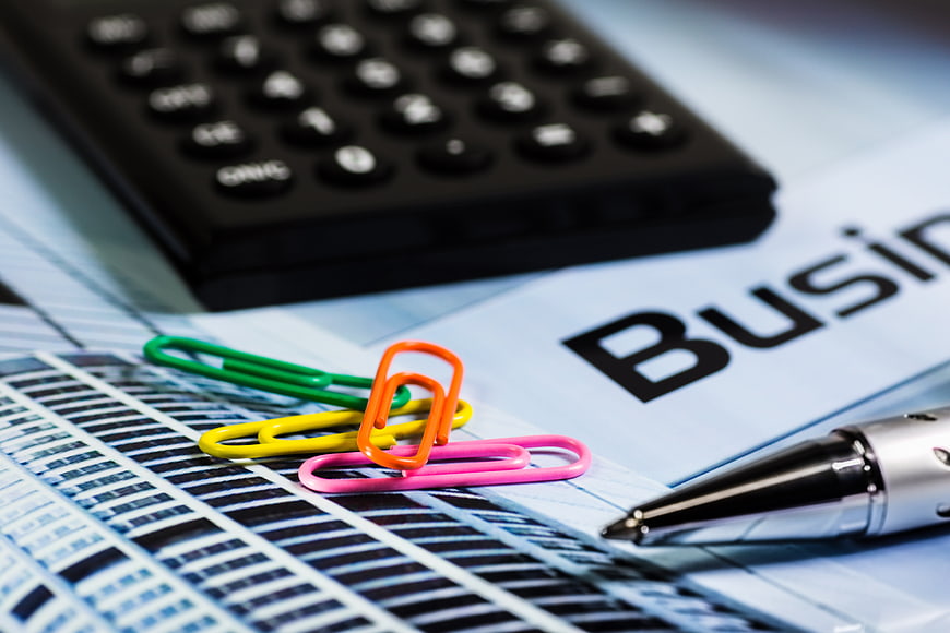 Business documents with calculator, pen, and colorful paperclips