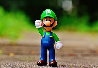 Luigi toy figure standing on a path with green background