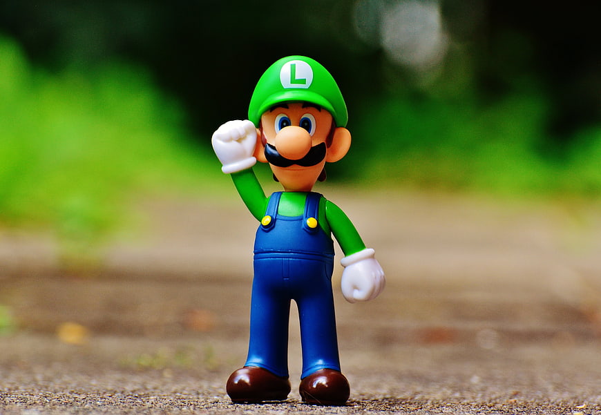 Luigi toy figure standing on a path with green background