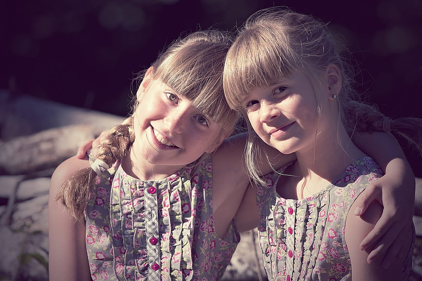 Portrait of Two Smiling Blonde Girls in Matching Dresses