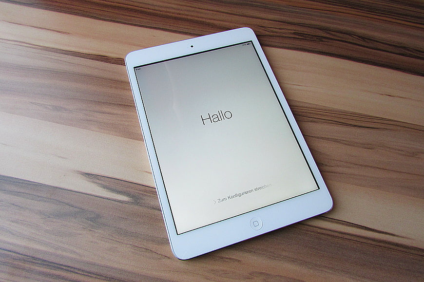 White tablet displaying German setup screen on wooden table