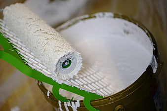 Paint roller and bucket with white paint for home renovation