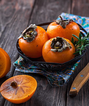 Fresh Orange Persimmons in Black Bowl on Rustic Wood
