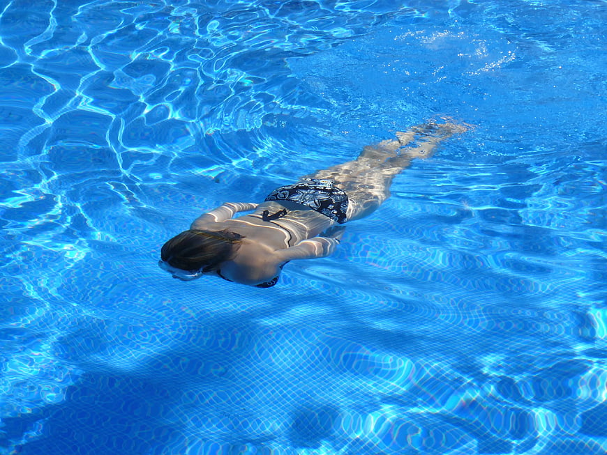 Woman swimming underwater in a blue pool