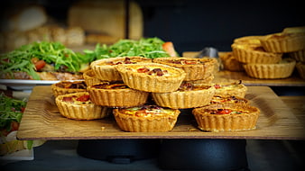 Stacked savory quiche tarts on wooden serving board