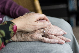 Close-up of elderly hands with wedding ring receiving comfort