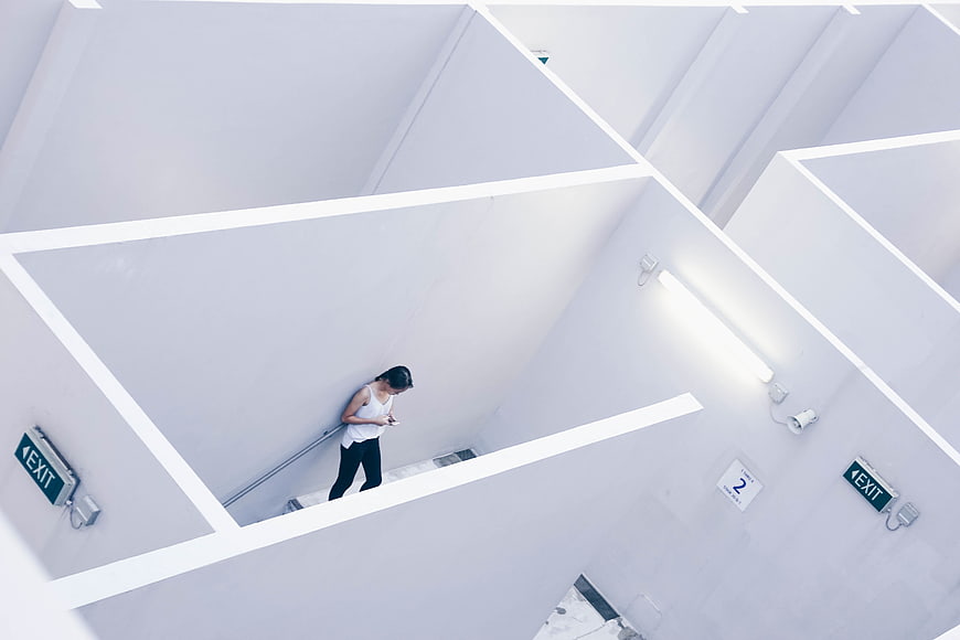 Woman texting on smartphone in minimalist white stairwell