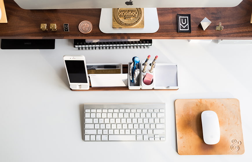 Top-down view of organized white office desk with computer and accessories
