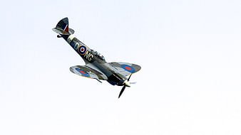 Vintage Spitfire Fighter Plane in Flight Against White Sky