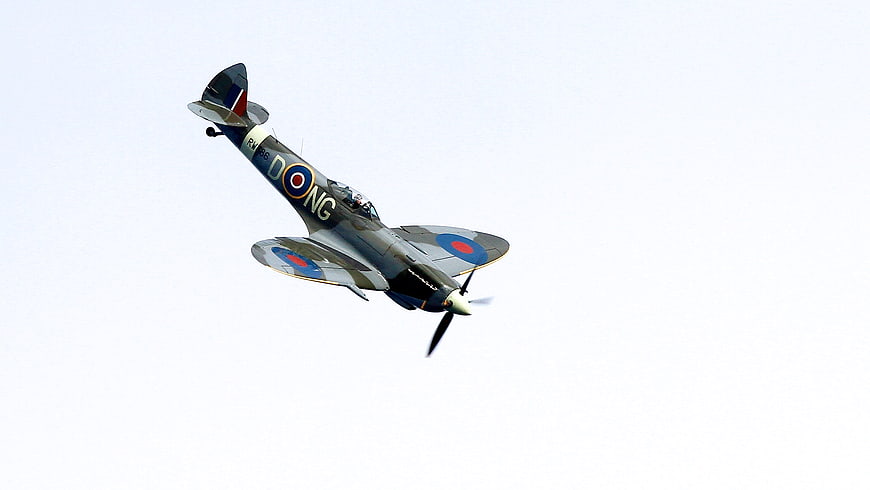 Vintage Spitfire Fighter Plane in Flight Against White Sky