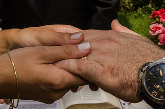 Close-up of hands holding a wedding ring and open bible