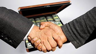 Business handshake over briefcase full of cash
