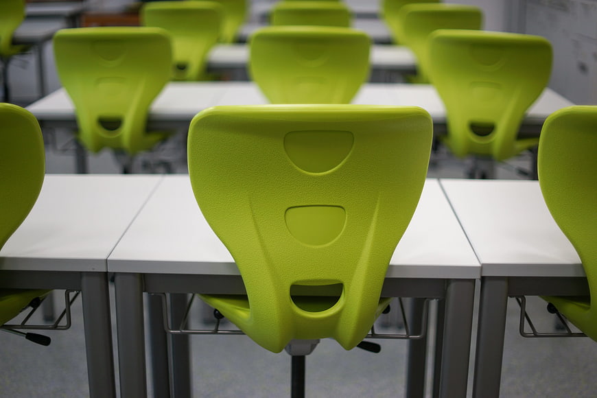 Rows of green chairs in an empty modern classroom