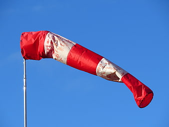 Red and white windsock fluttering against a clear blue sky
