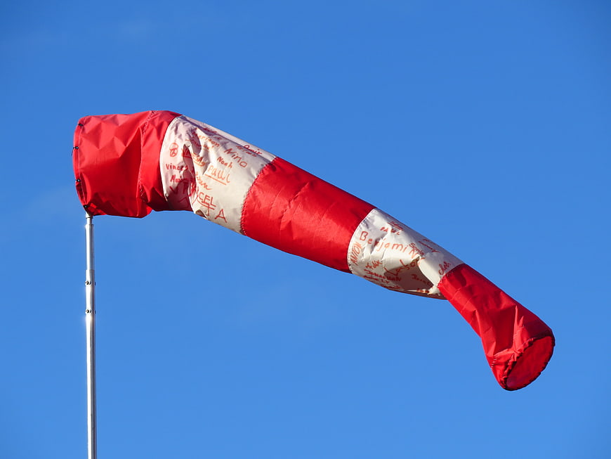 Red and white windsock fluttering against a clear blue sky