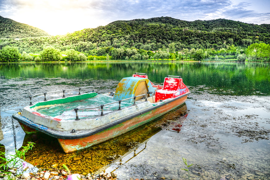 Abandoned colorful pedal boat on a lake shore