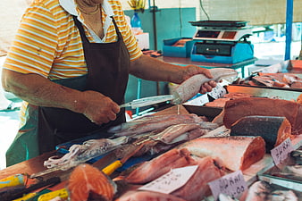 Fishmonger cutting fresh squid at outdoor seafood market stall
