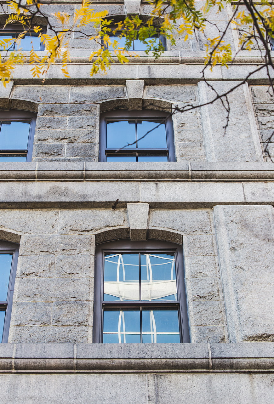 Stone building facade with arched windows and autumn leaves
