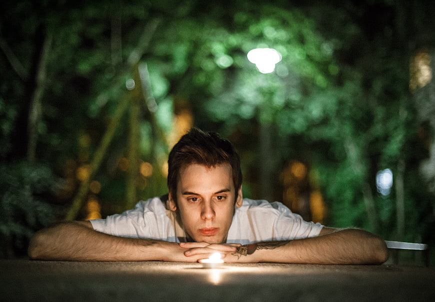 Young man meditating with candle at night in park