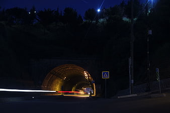 Night long exposure of a stone tunnel with car light trails