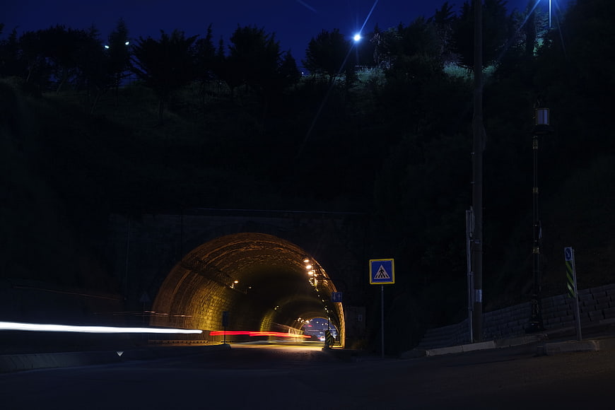 Night long exposure of a stone tunnel with car light trails