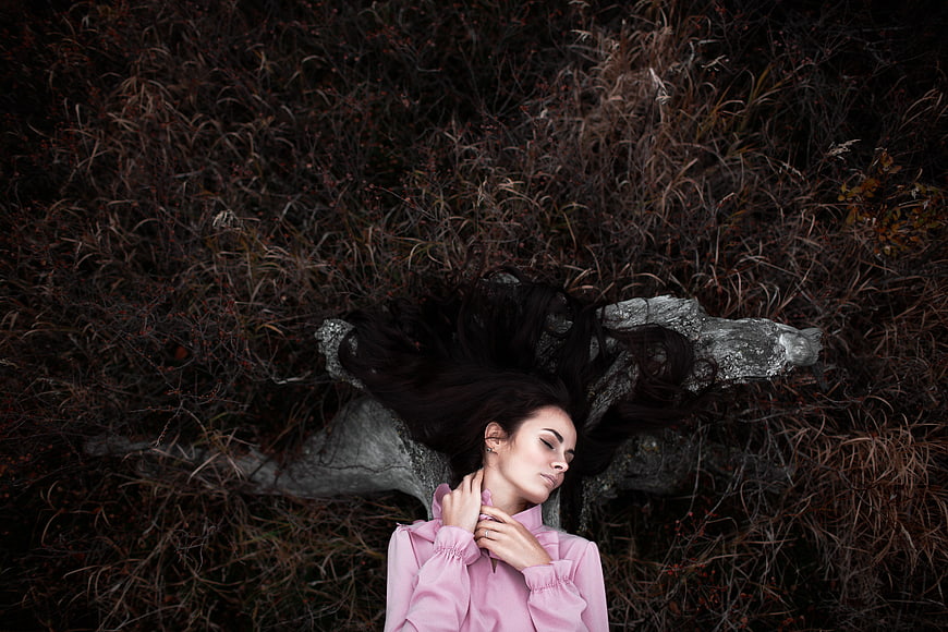 Woman in Pink Blouse Lying on Log in Autumn Forest