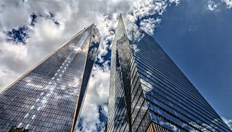 Low angle view of modern glass skyscrapers against a cloudy blue sky