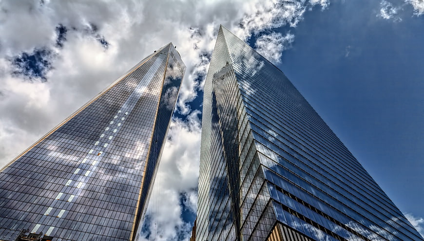 Low angle view of modern glass skyscrapers against a cloudy blue sky