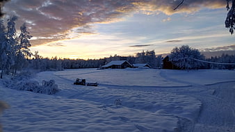Snowmobile in Winter Landscape with Wooden Cabin at Sunset