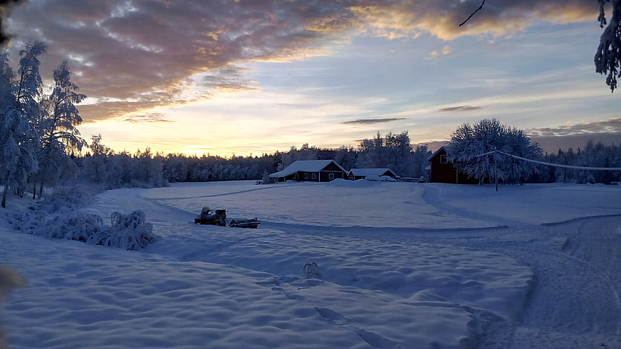 Snowmobile in Winter Landscape with Wooden Cabin at Sunset