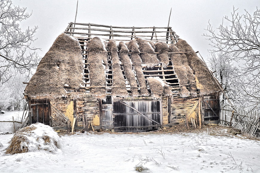 Dilapidated Thatched Roof Barn in Snowy Winter Landscape