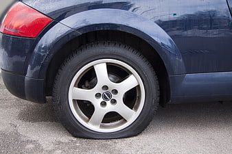 Close-up of a flat tire on a dark blue Subaru Forester