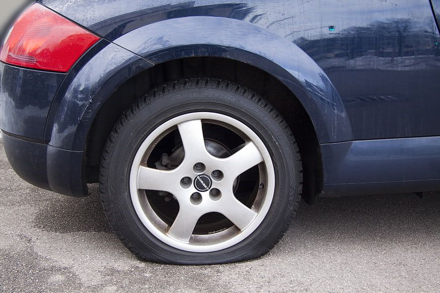 Close-up of a flat tire on a dark blue Subaru Forester