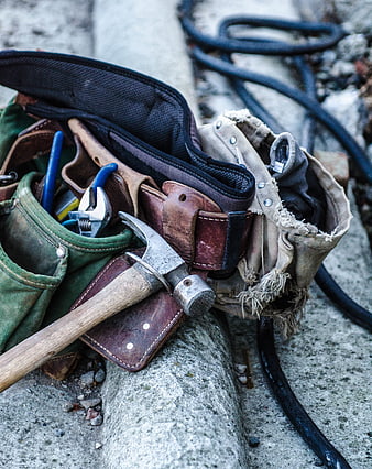 Worn Leather Tool Belt with Hammer and Pliers on Concrete
