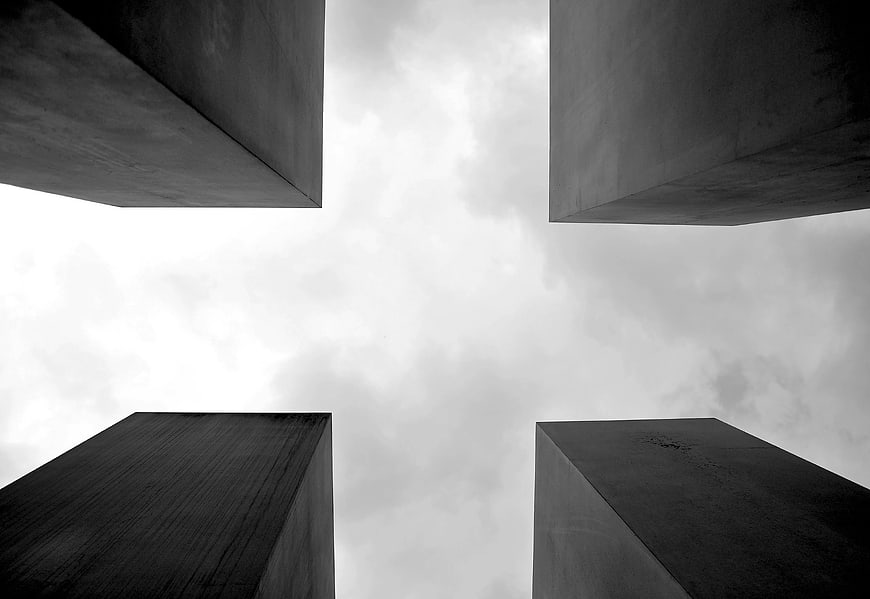 Low angle view of four concrete pillars against cloudy sky