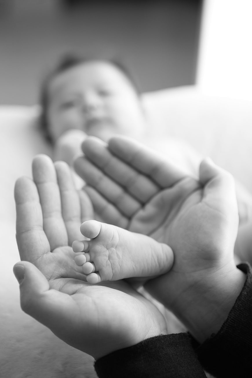 Black and white photo of baby foot in adult hands