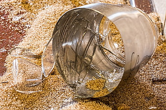 Broken glass cup shattered on sawdust background