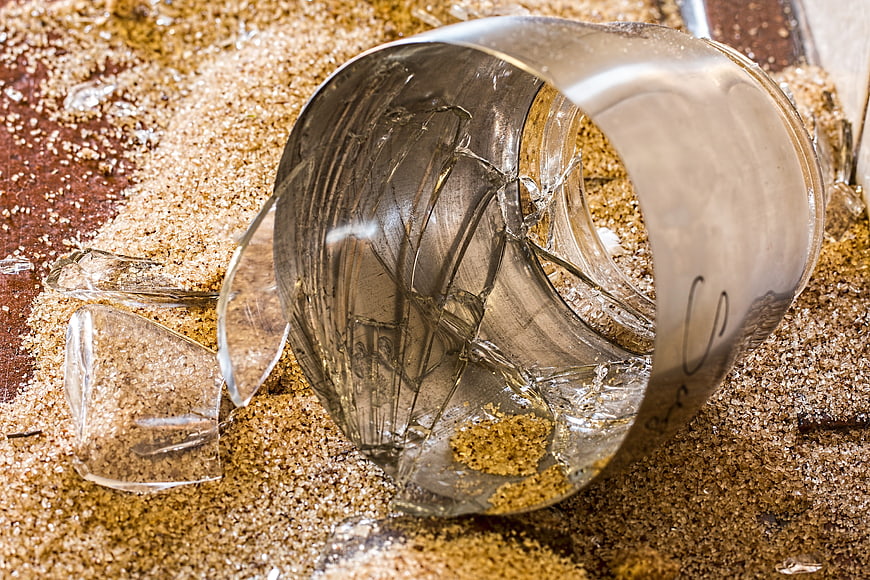 Broken glass cup shattered on sawdust background