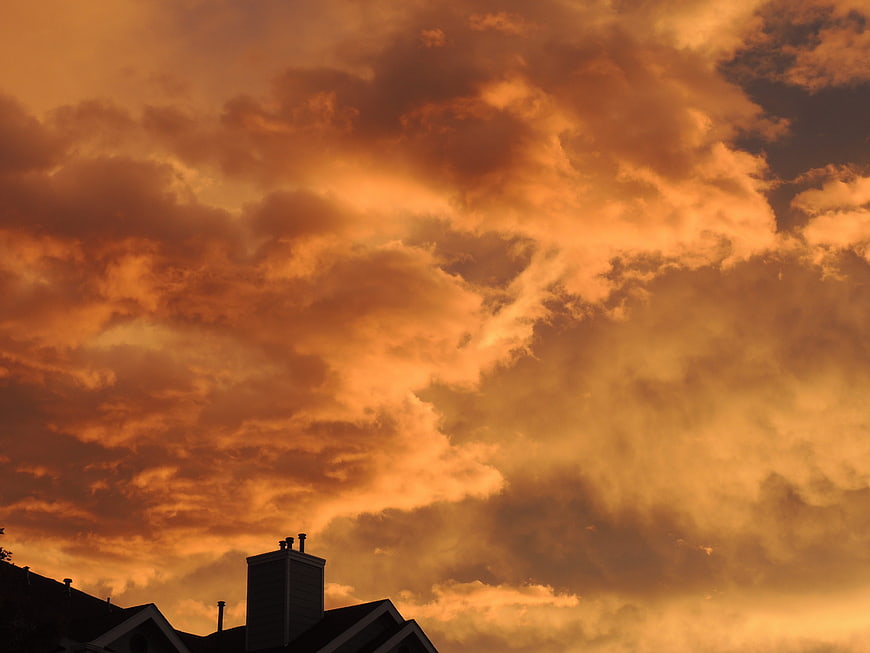 Dramatic orange sunset sky with silhouetted house roof