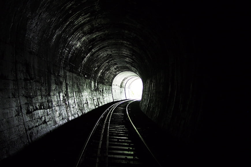 Dark Railway Tunnel With Bright Exit And Curved Train Tracks