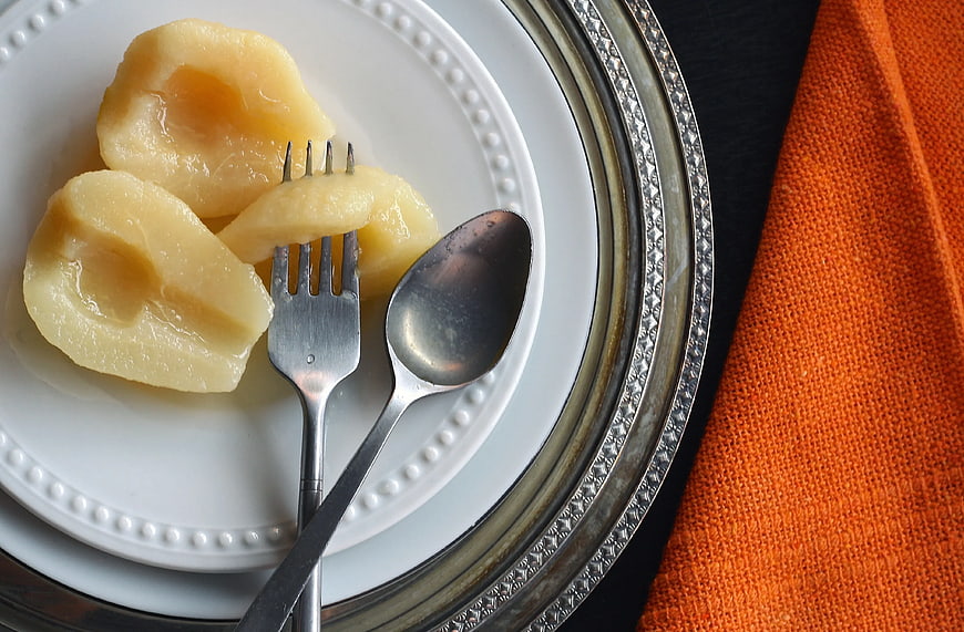 Poached Pears on White Plate with Silver Cutlery