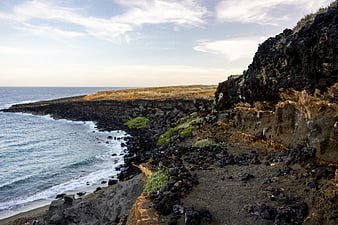 Rugged volcanic coastline with ocean waves and rocky cliffs