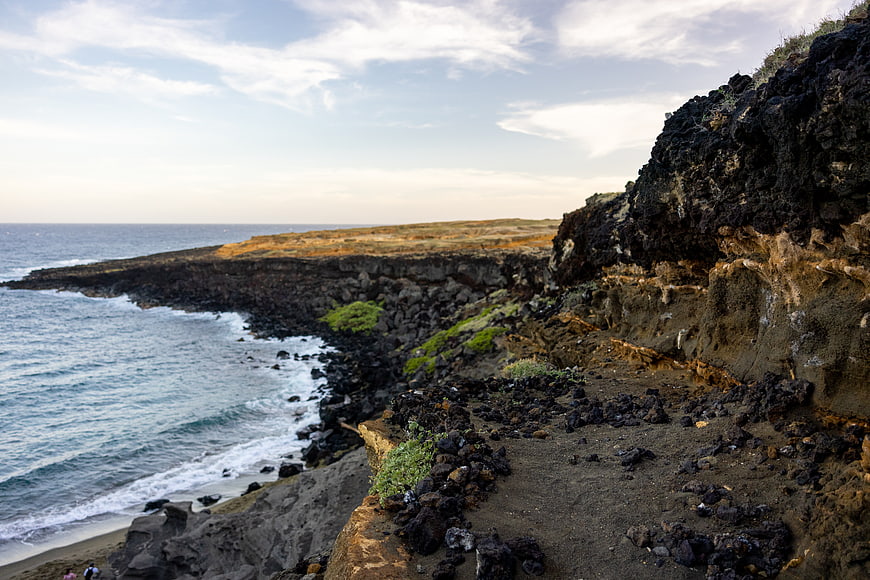 Rugged volcanic coastline with ocean waves and rocky cliffs