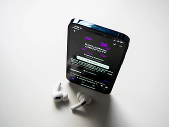 Smartphone Playing Podcast with Wireless Earbuds on White Surface