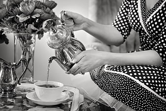 Vintage woman pouring tea from silver teapot in black and white