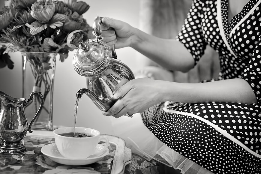 Vintage woman pouring tea from silver teapot in black and white