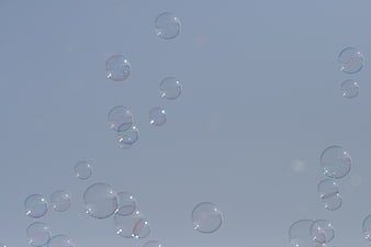 Soap Bubbles Floating Against a Soft Blue Sky Background