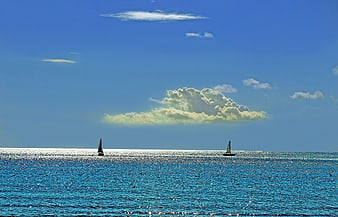Sailboats on Sparkling Blue Ocean Under Cloudy Sky